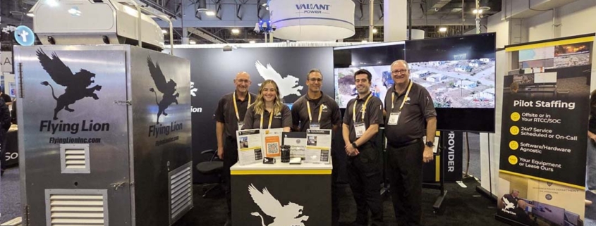 Flying Lion team at their ISC West trade show booth showcasing the DroneBooth™ rapid-deploy drone dock enclosure alongside pilot staffing services signage.