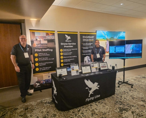Flying Lion team members at their exhibit booth displaying drone services, drone-in-a-box technology, and public safety UAS solutions.